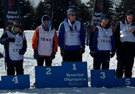  special olympic athletes stand behind podium with medals around their necks